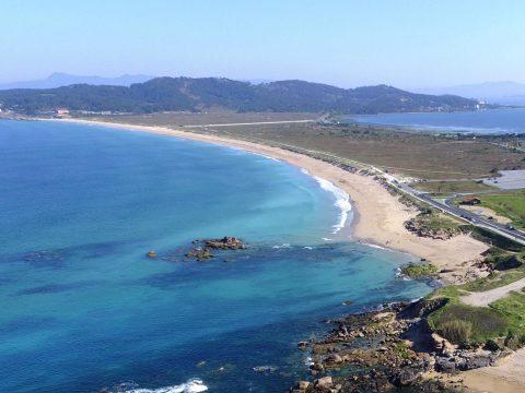 Panorámica de A Lanzada con carretera litoral y mar azul, destino de playa en Galicia
